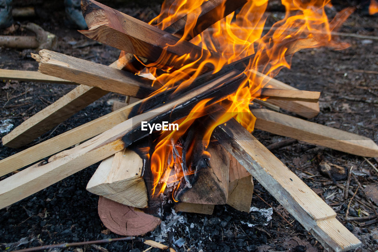 A fire burns in a campfire with a red fire in the background.