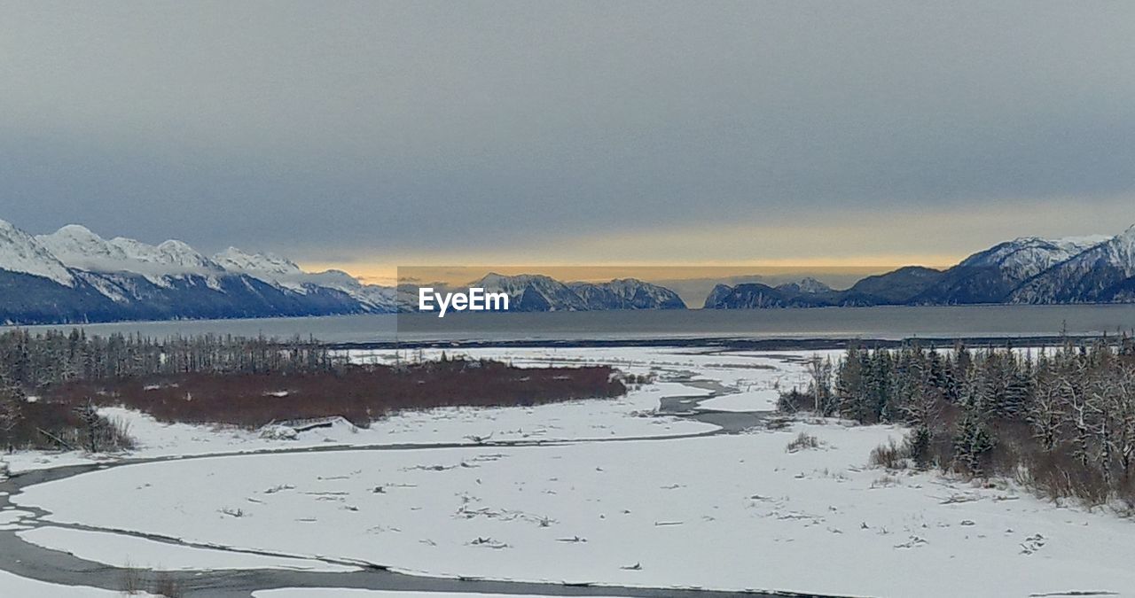 SCENIC VIEW OF LAKE AGAINST SNOWCAPPED MOUNTAINS DURING WINTER