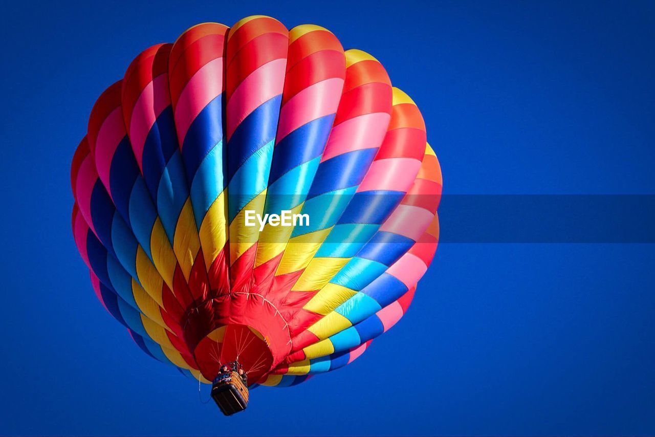 LOW ANGLE VIEW OF COLORFUL HOT AIR BALLOON AGAINST BLUE SKY