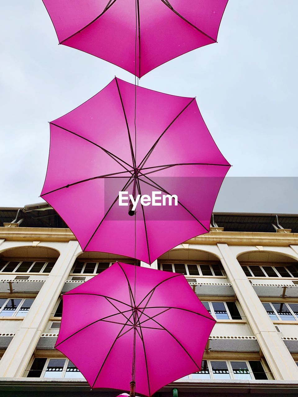 LOW ANGLE VIEW OF MULTI COLORED UMBRELLAS AGAINST SKY