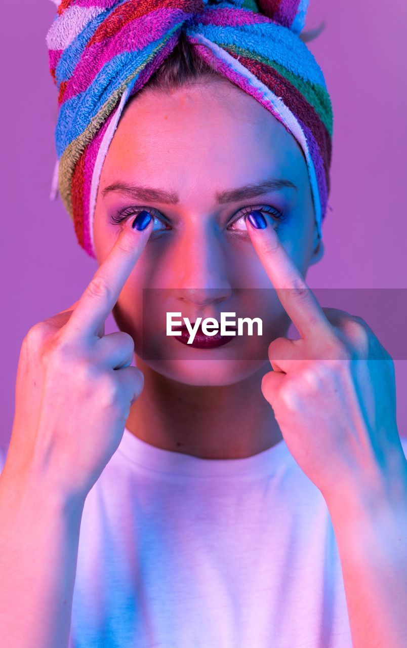 Close-up portrait of young woman showing middle finger over pink background