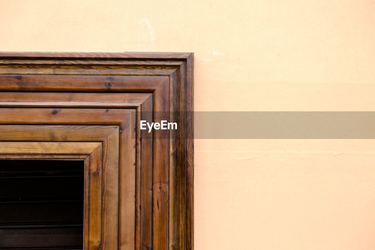 Wooden dark brown solid wood frame corner contrasting to light cream wall