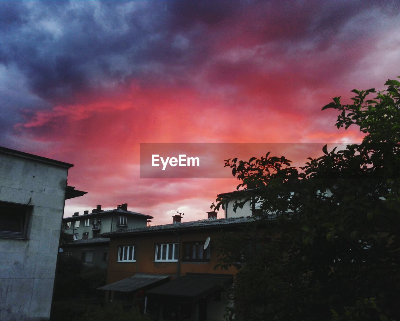 Houses against cloudy sky during sunset