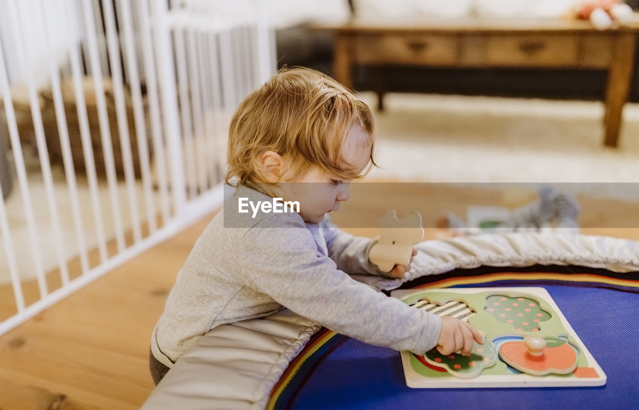 Side view of girl playing with toys at home