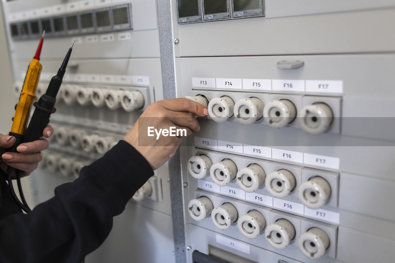 Hand of female technician operating electrical fuse box