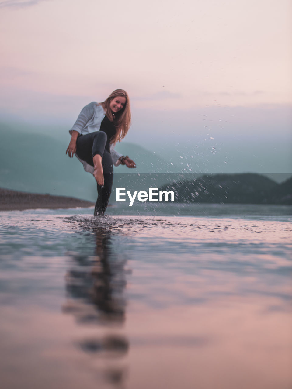 Full length of woman in sea against sky during sunset