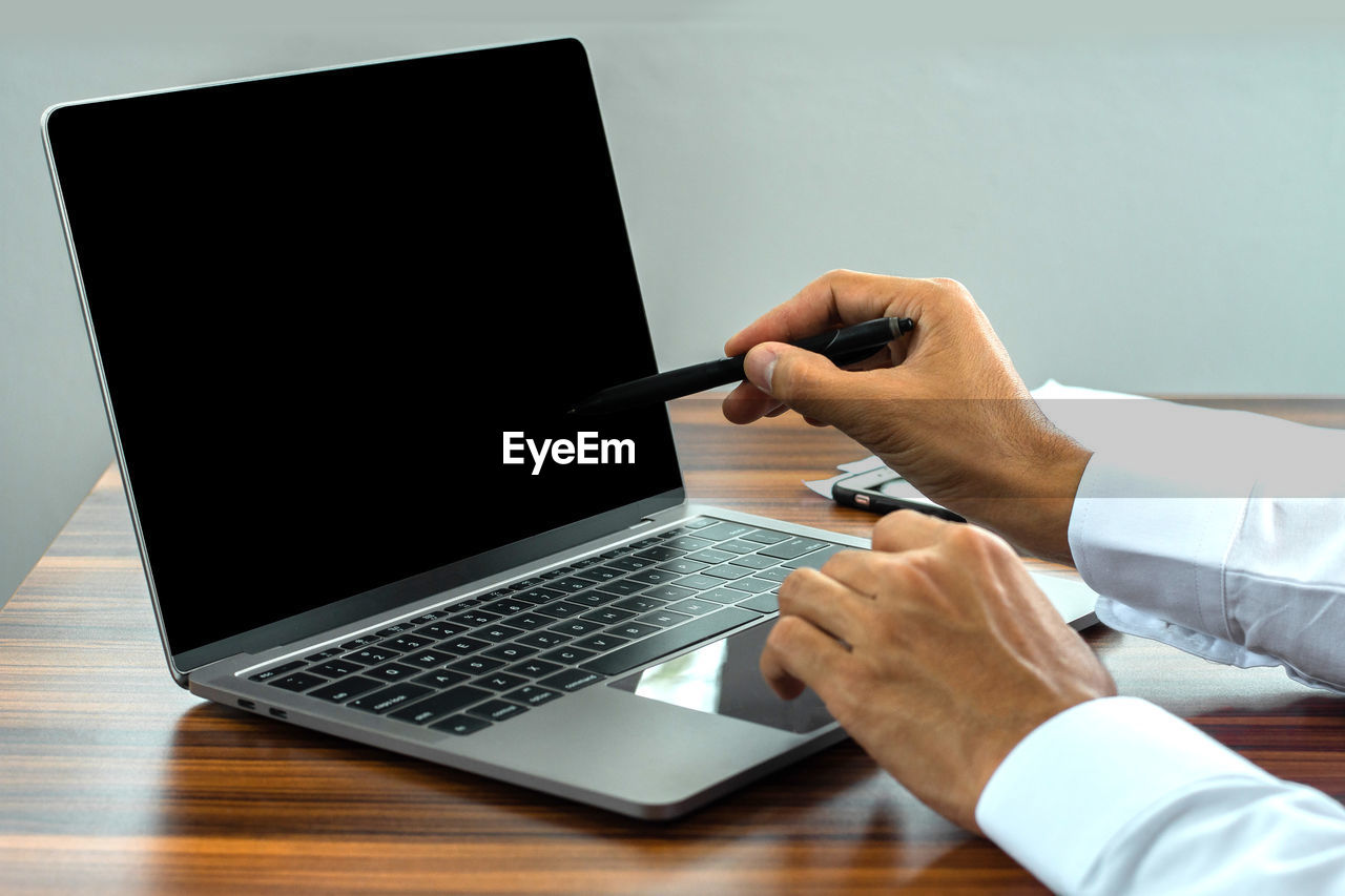 LOW ANGLE VIEW OF MAN USING LAPTOP