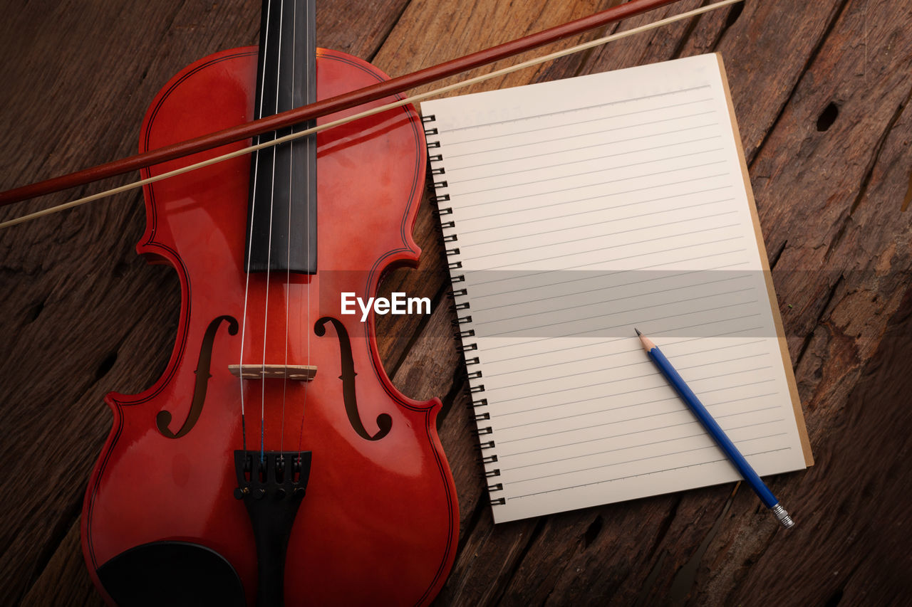 High angle view of violin by spiral notebook and pencil on table