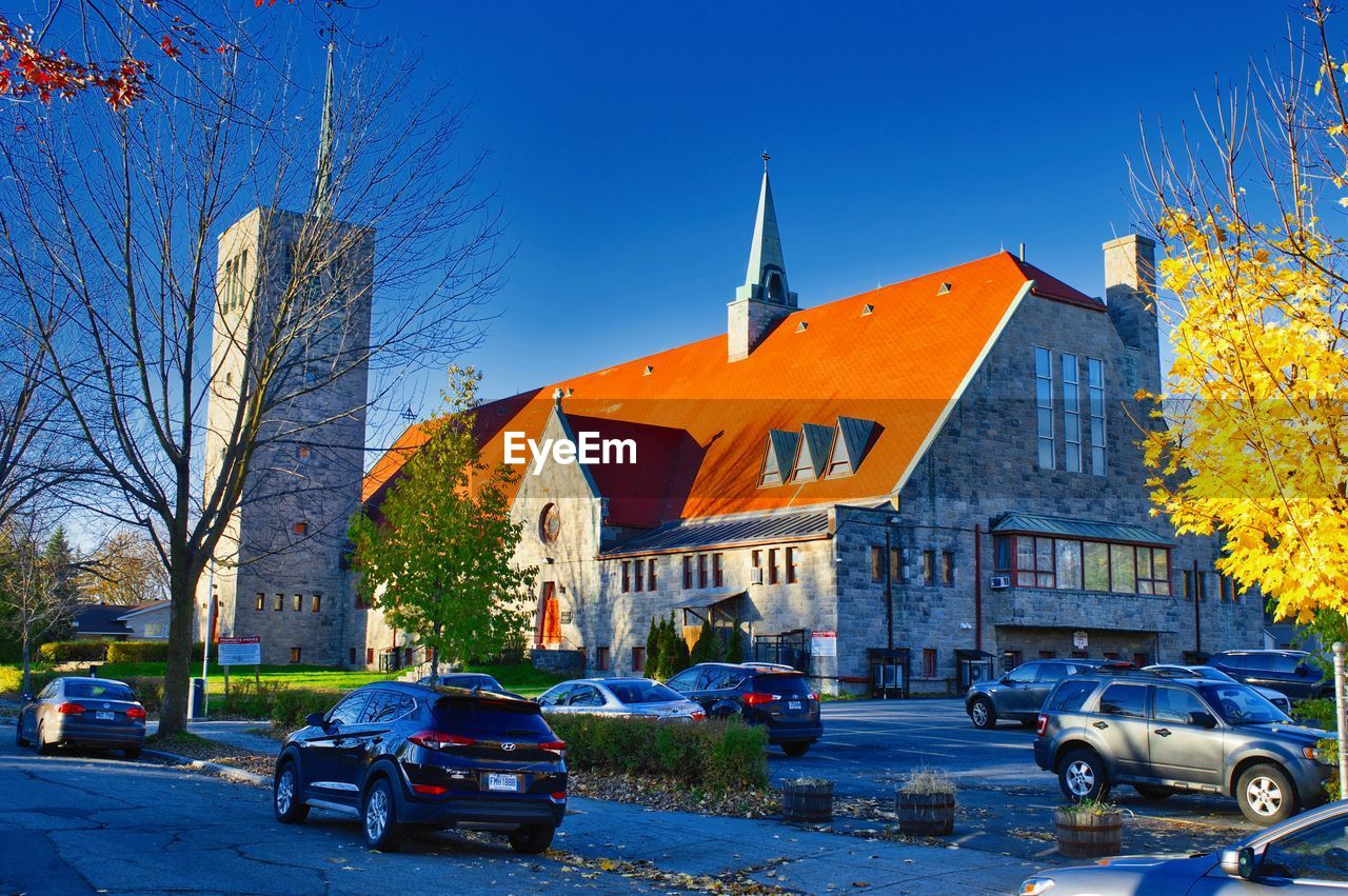 CARS ON ROAD AMIDST BUILDINGS AGAINST CLEAR BLUE SKY