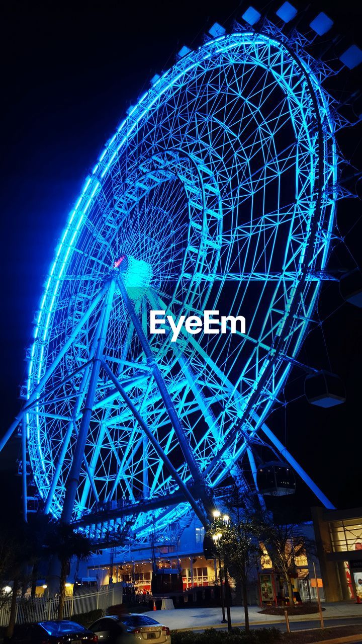 LOW ANGLE VIEW OF ILLUMINATED FERRIS WHEEL AT NIGHT