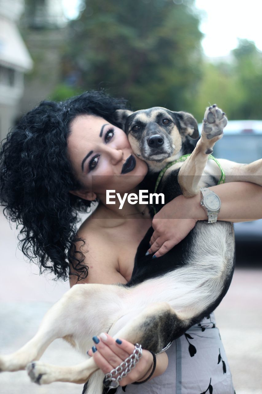 Portrait of smiling woman with dog standing outdoors