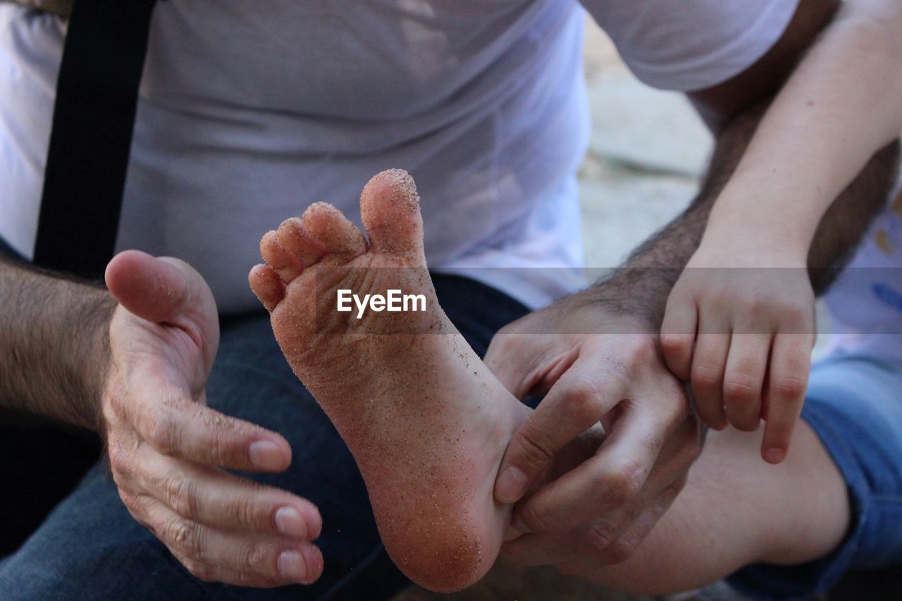 Midsection of man cleaning daughter dirty foot