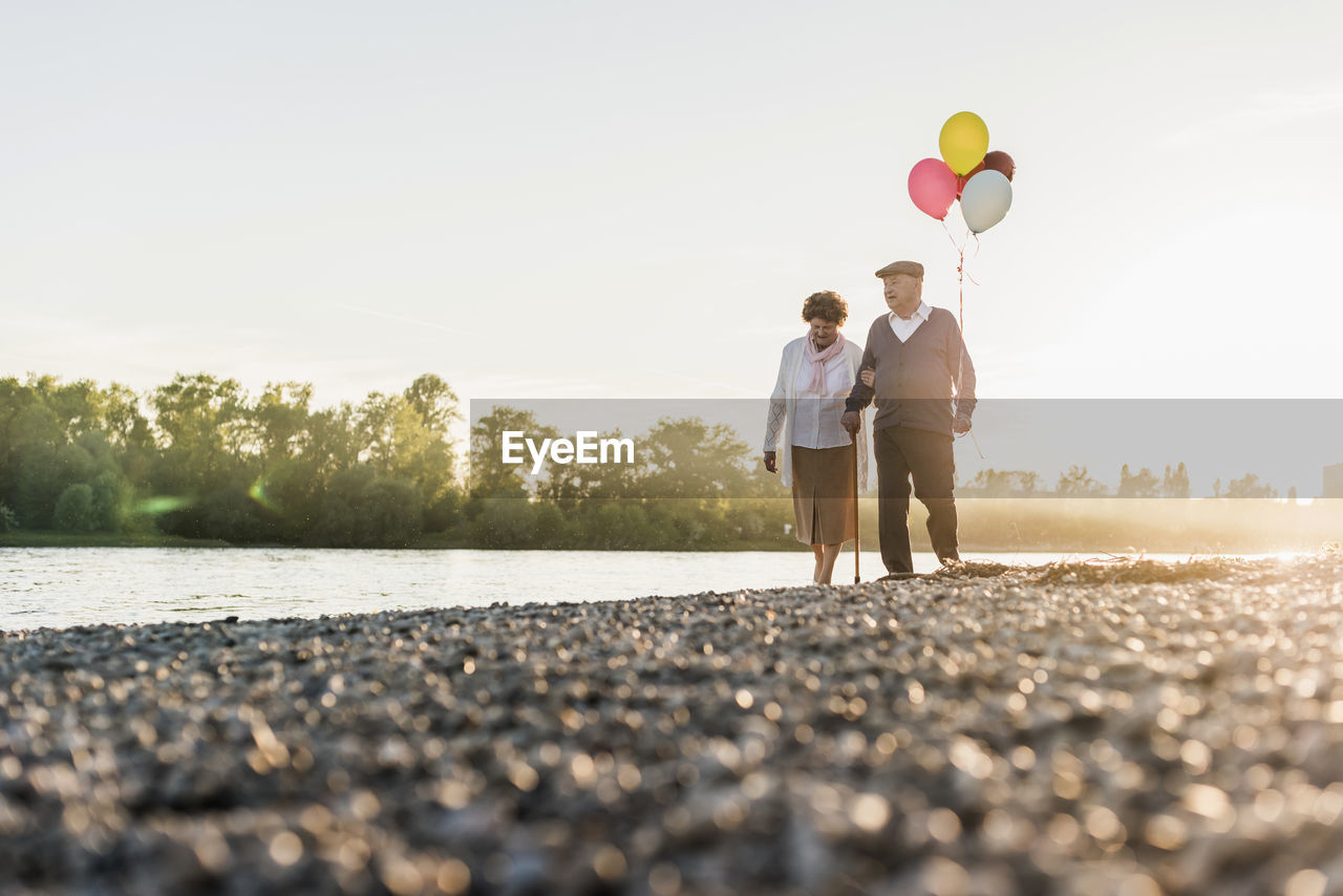 Senior couple with balloons strolling at riverside