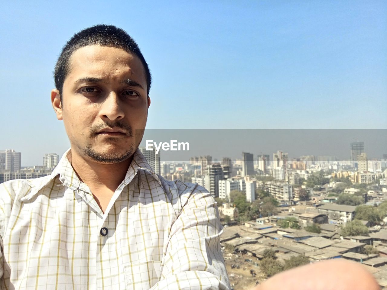 Portrait of young man in city against clear sky