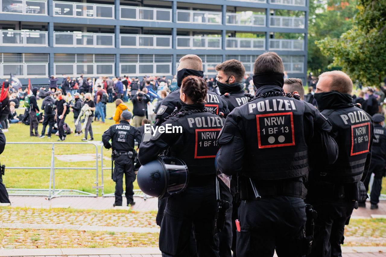 REAR VIEW OF PEOPLE STANDING IN FRONT OF OFFICE