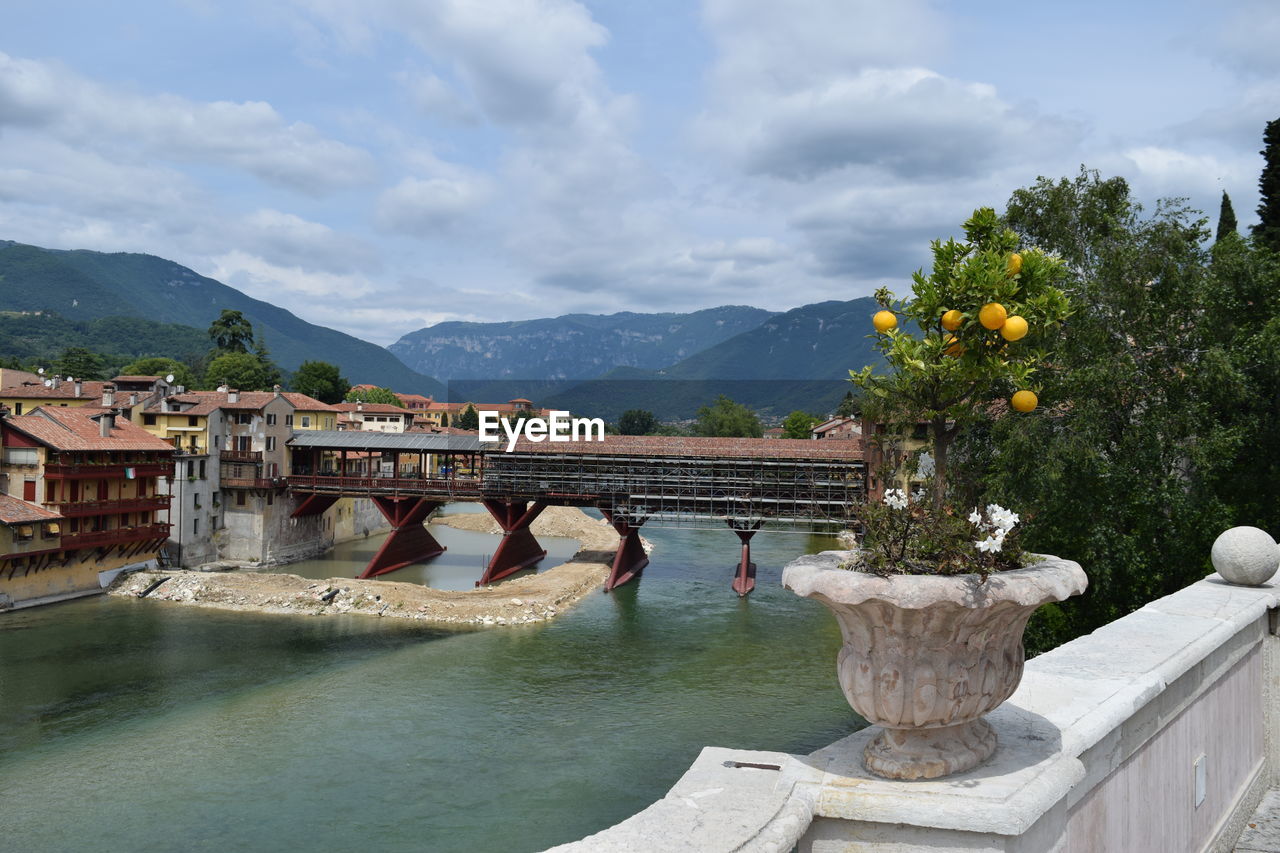 Arch bridge over river against cloudy sky