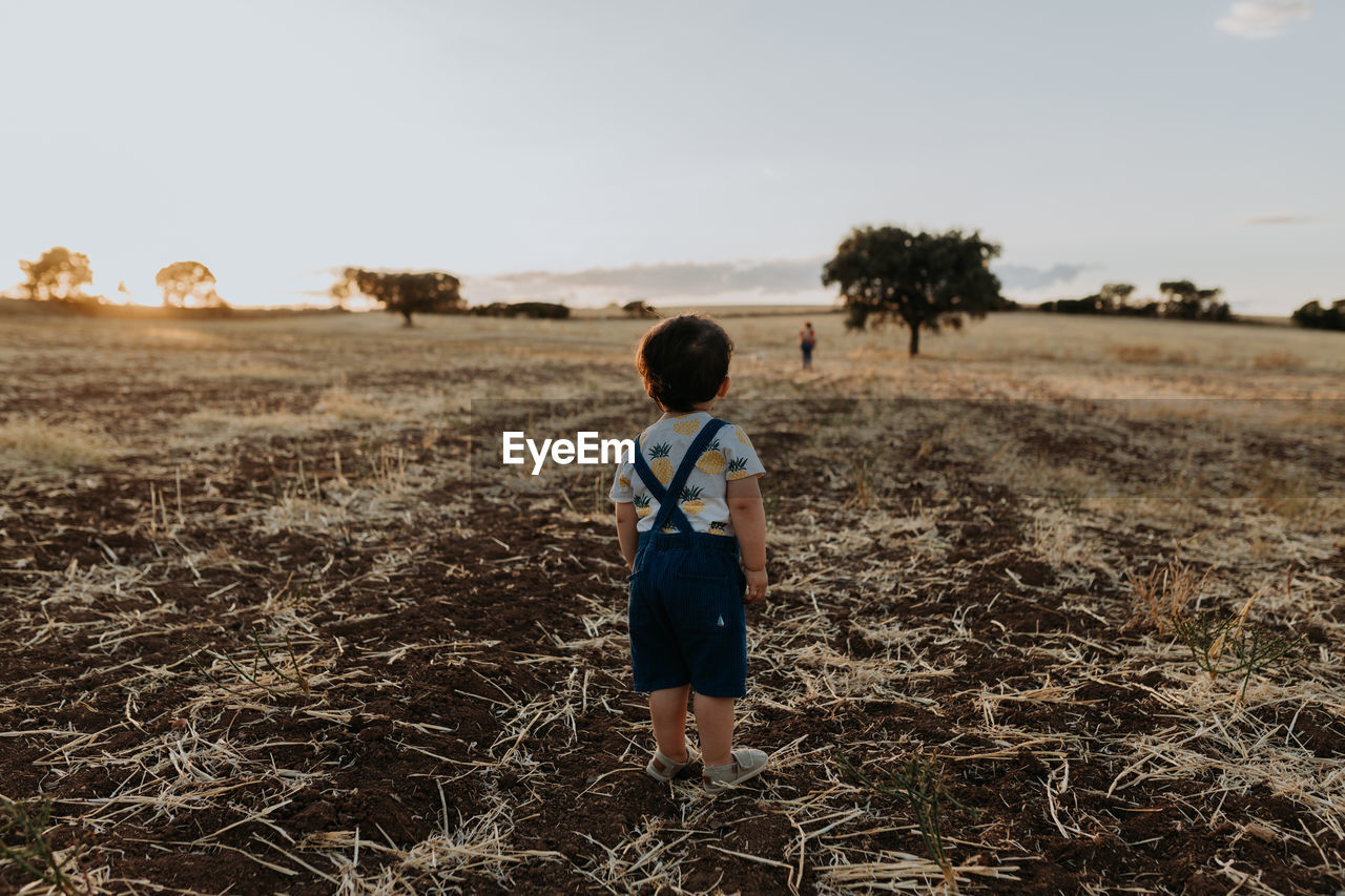 Rearview child standing on the fields