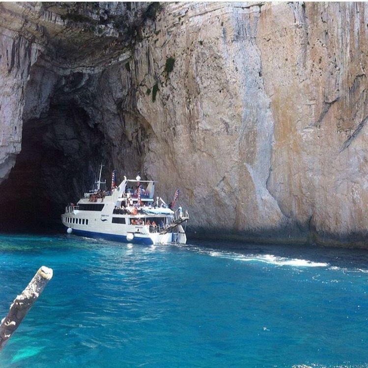 BOATS IN SEA WITH ROCKS IN BACKGROUND