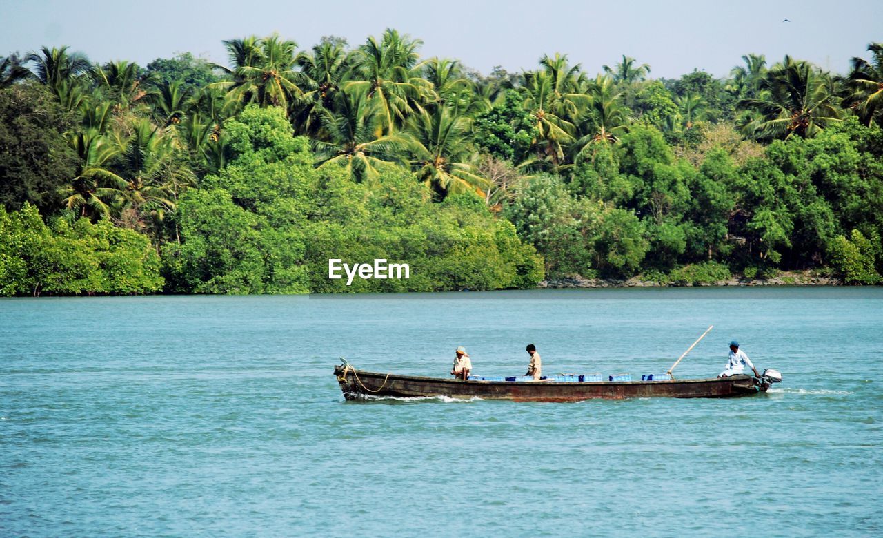 People on boat in sea against sky