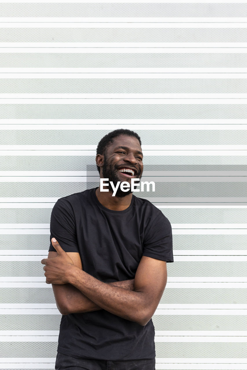 Content african american man in black t shirt standing looking at camera on light background