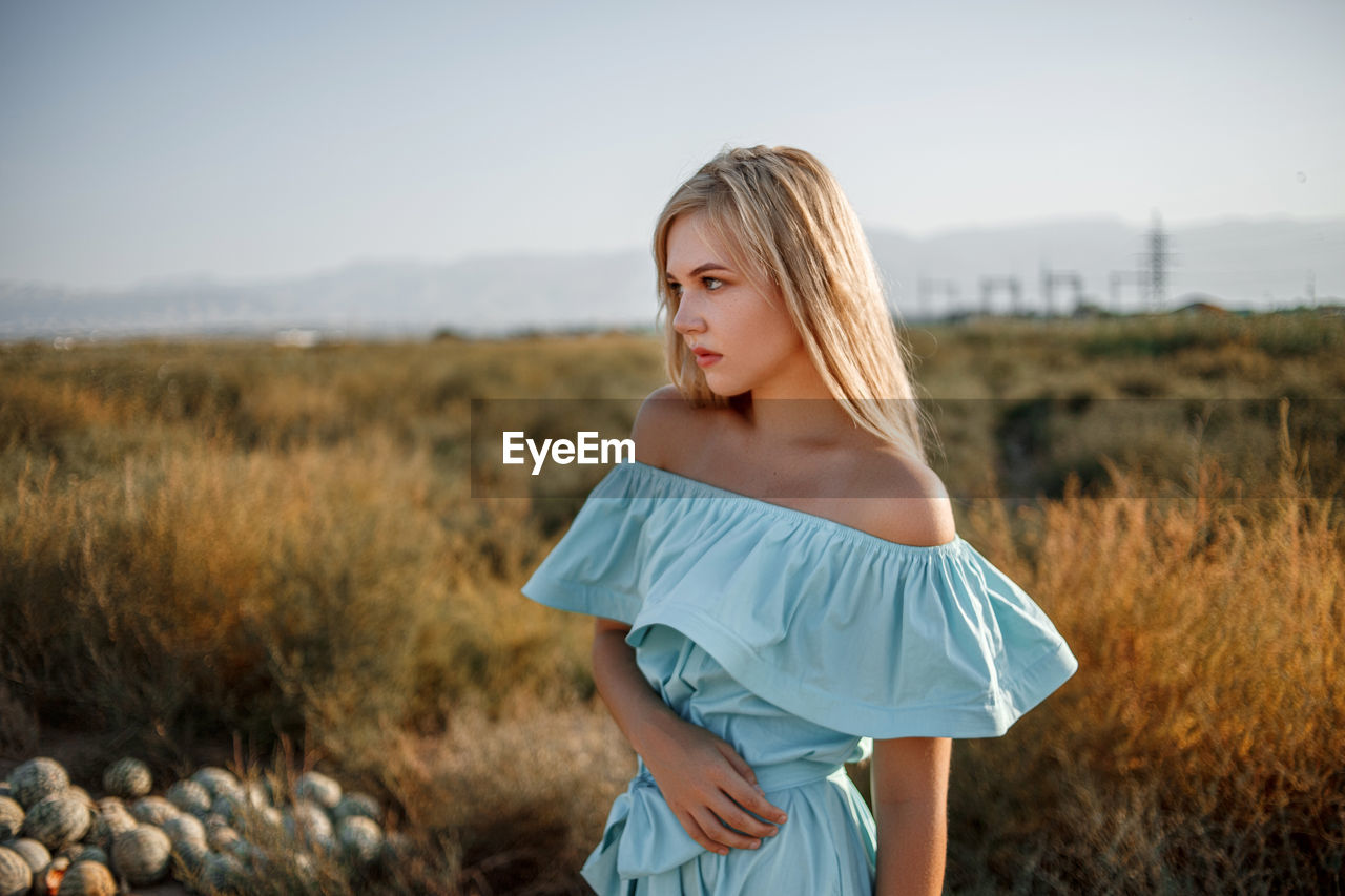 Teenage girl wearing dress standing on land against sky