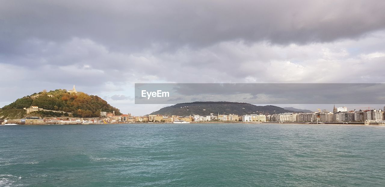 SCENIC VIEW OF SEA BY CITY BUILDINGS AGAINST SKY