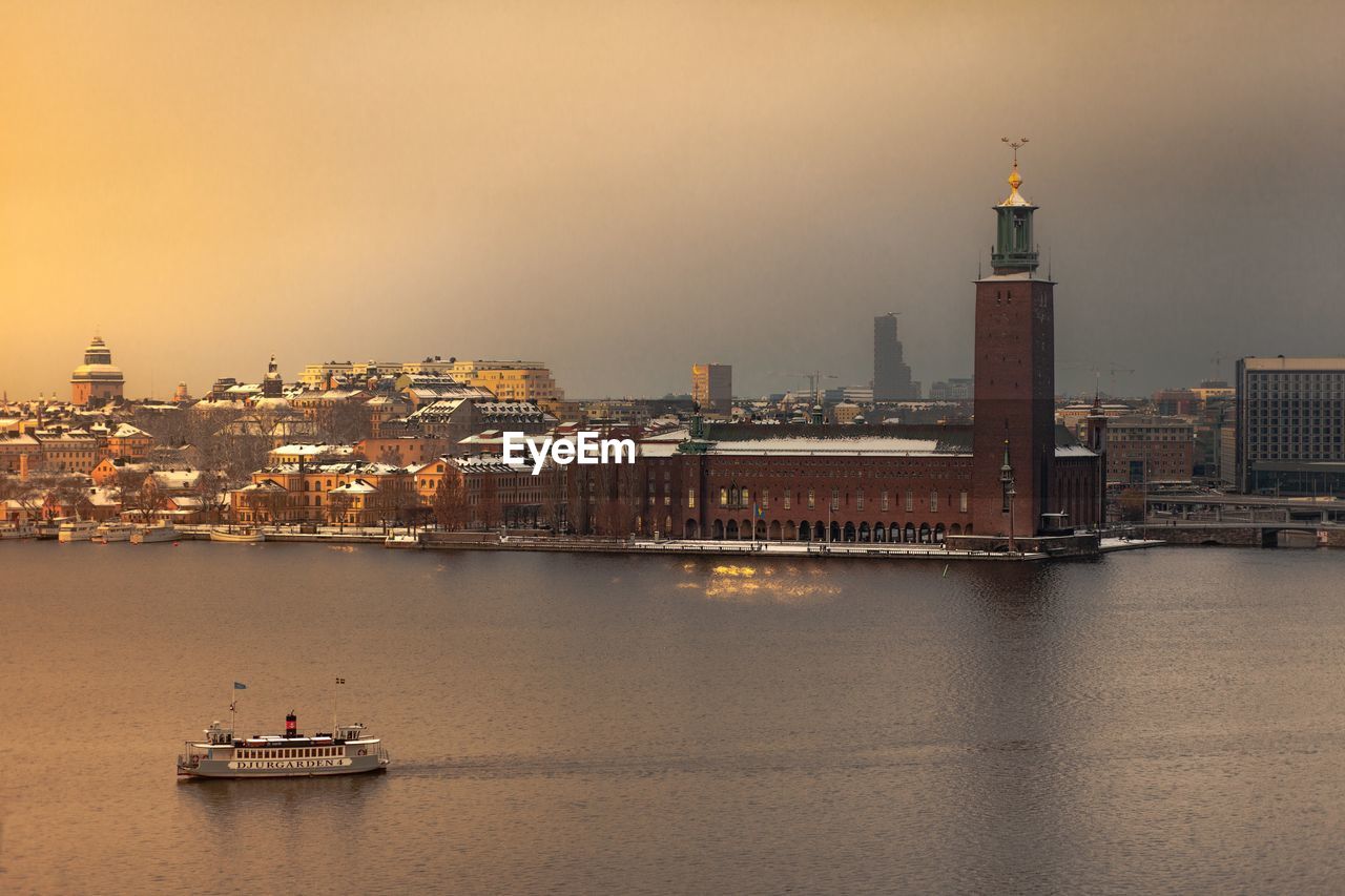 Buildings by sea against sky