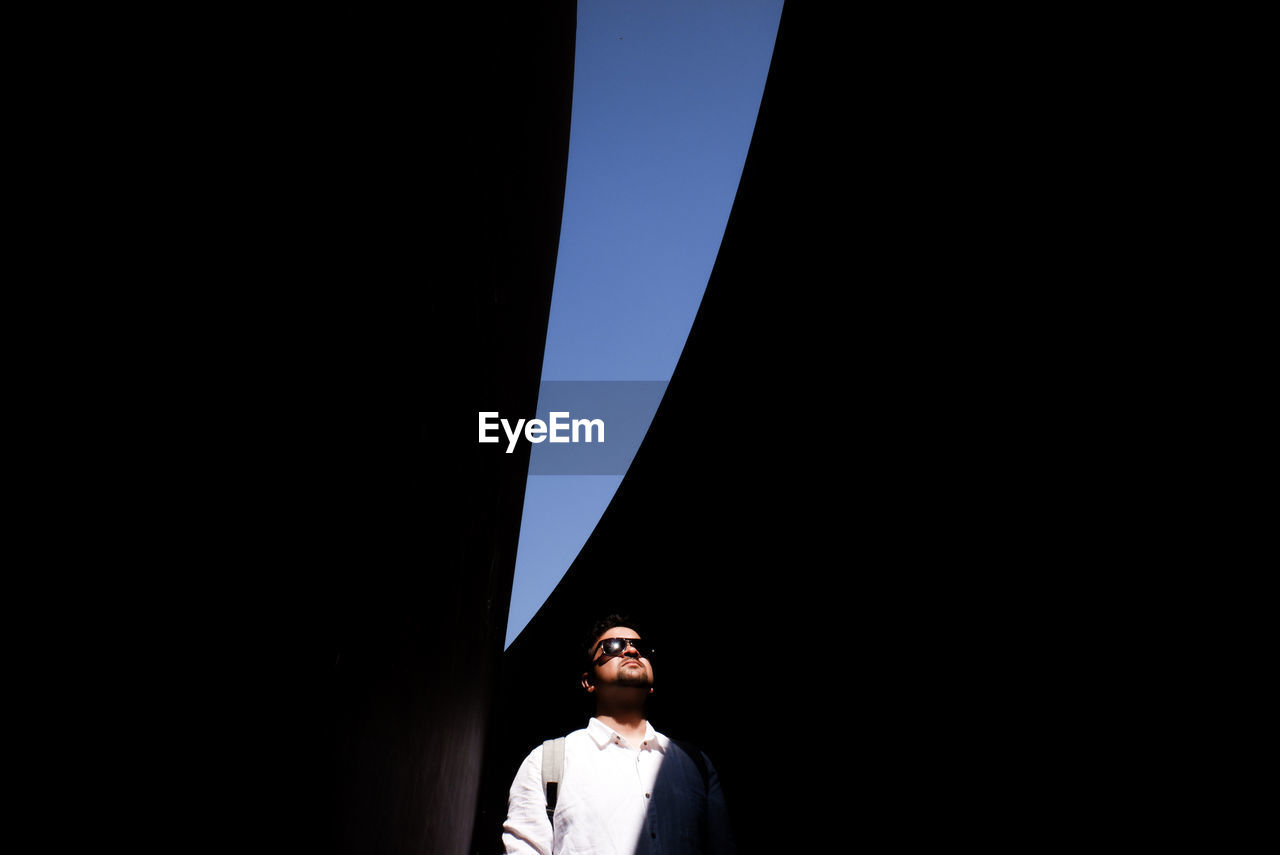 Young man standing below bridge