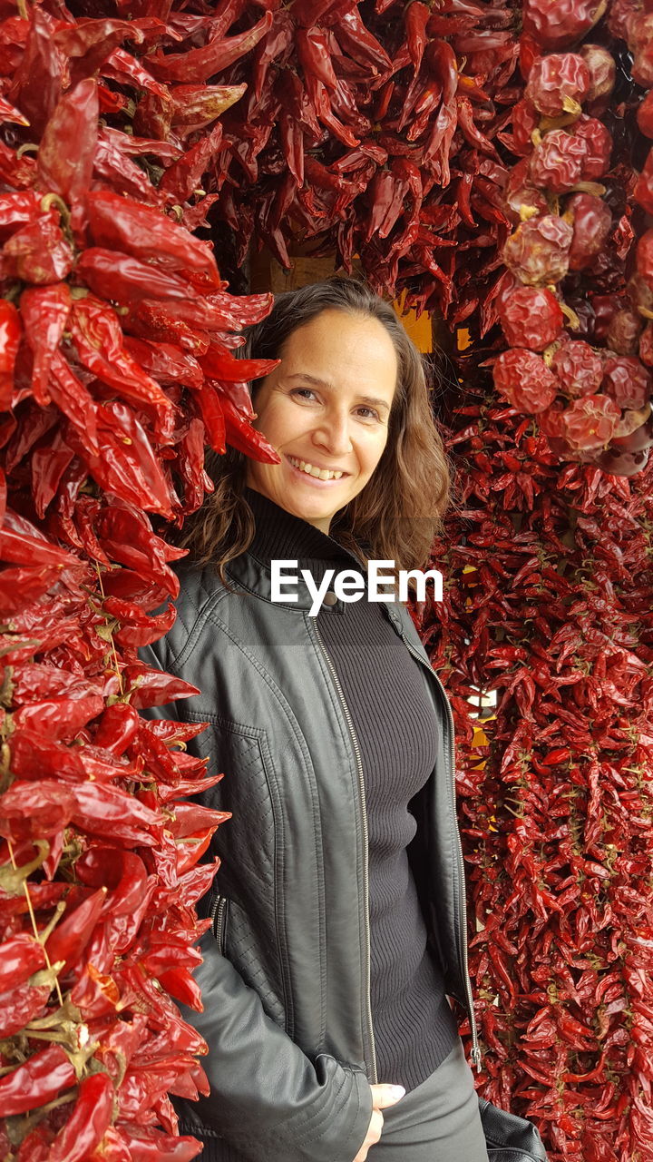 Portrait of mid adult woman standing by paprika at market stall