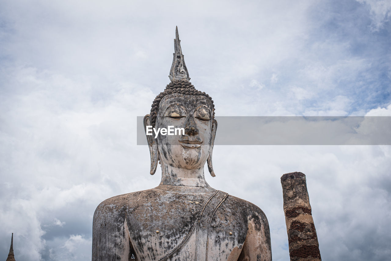 Low angle view of buddha statue against sky