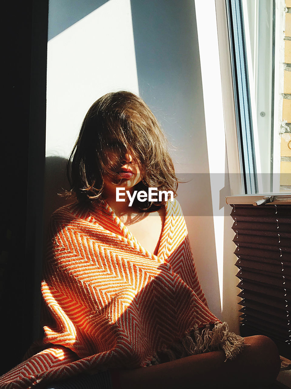Girl sitting by window at home