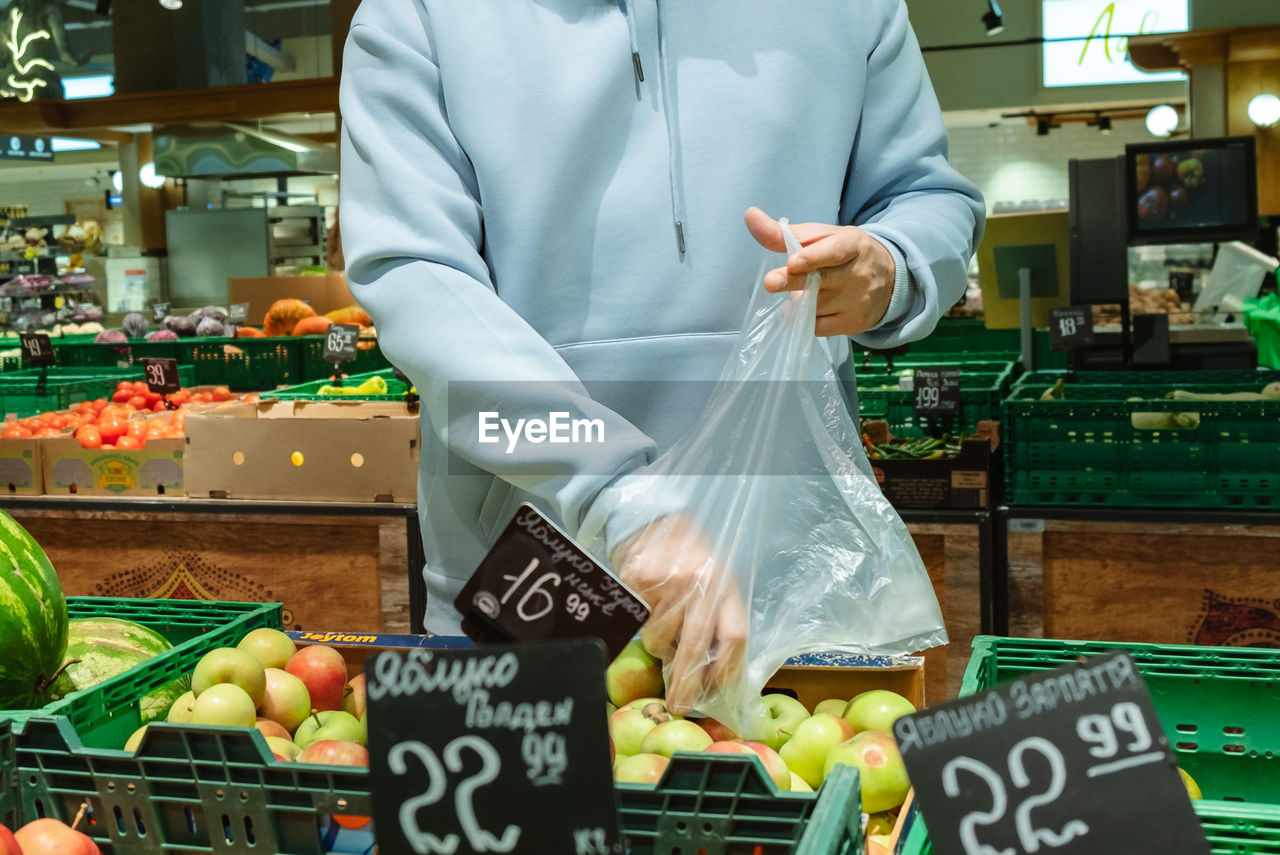 midsection of man holding vegetables for sale at market stall