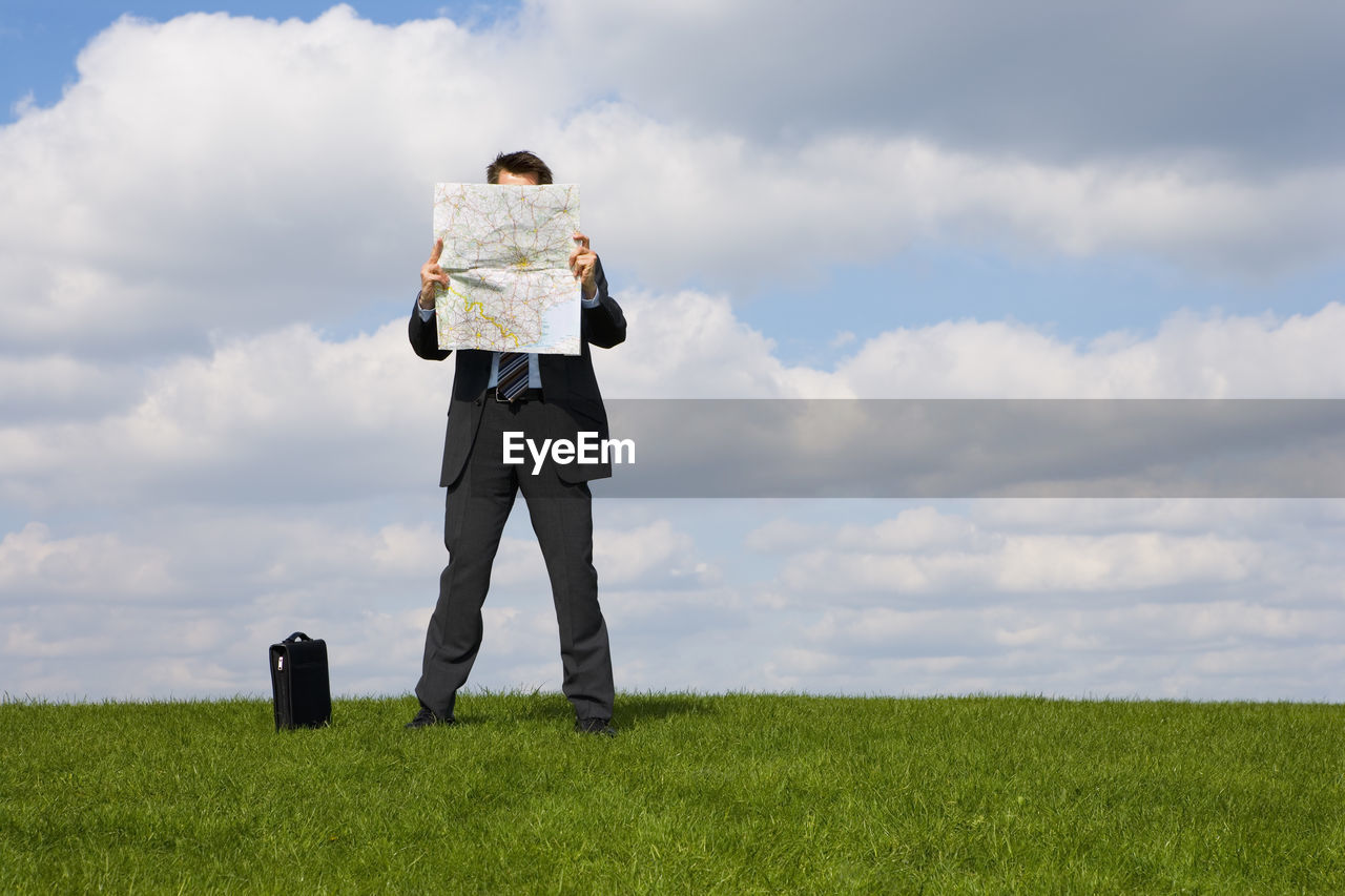 Man looking at map while standing on land against sky