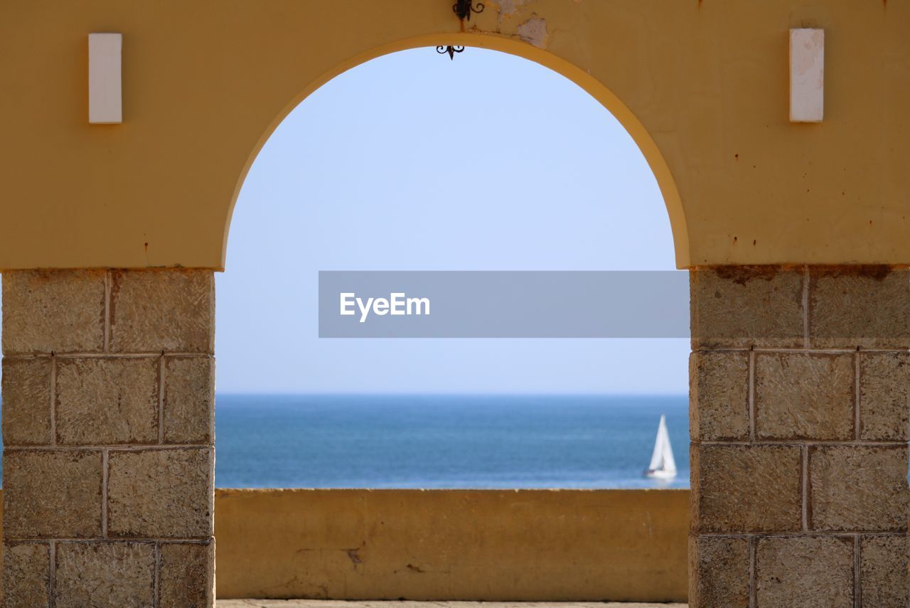 View of sea against clear sky seen through arch window