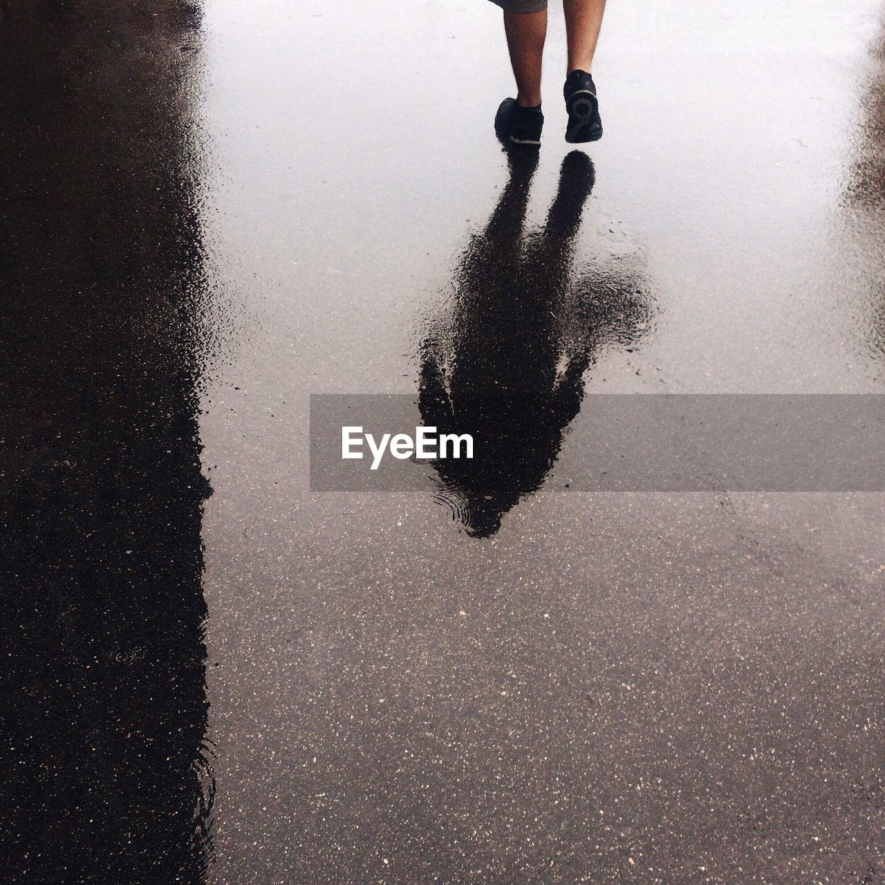 Low section of man walking on puddle during rainy season