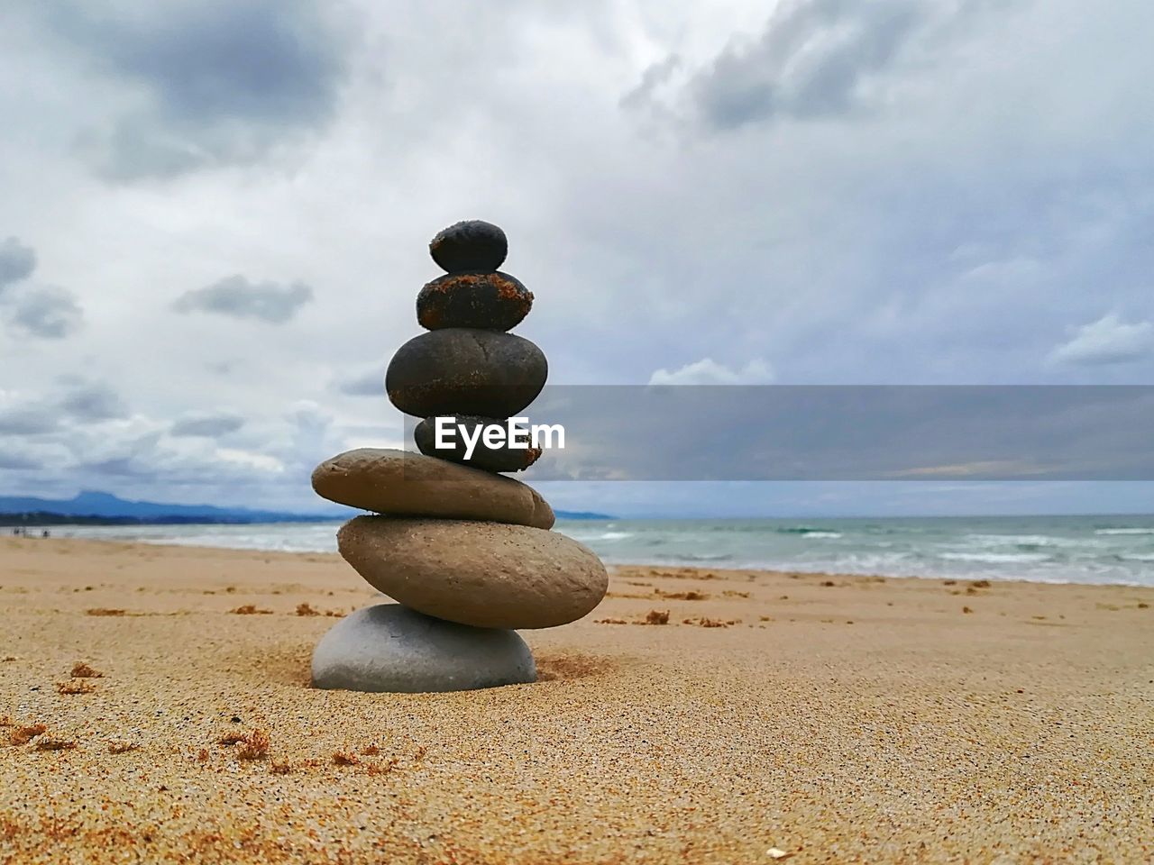 Stack of pebbles on beach against sky