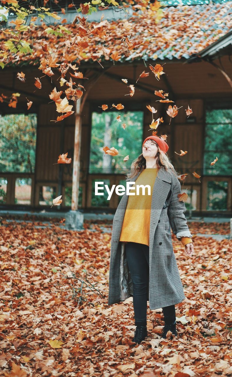 WOMAN STANDING BY MAPLE TREE