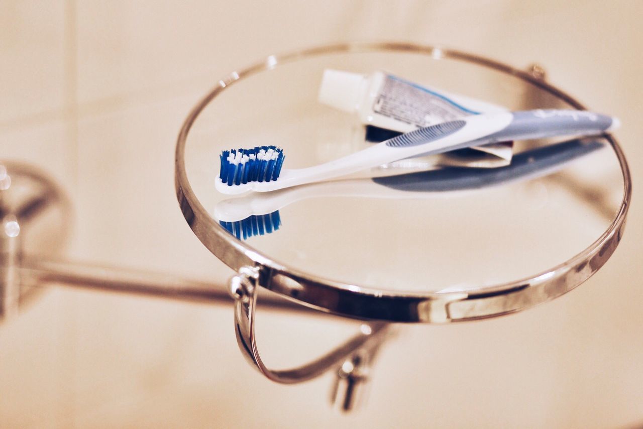 Close-up of toothbrush with toothpaste on mirror