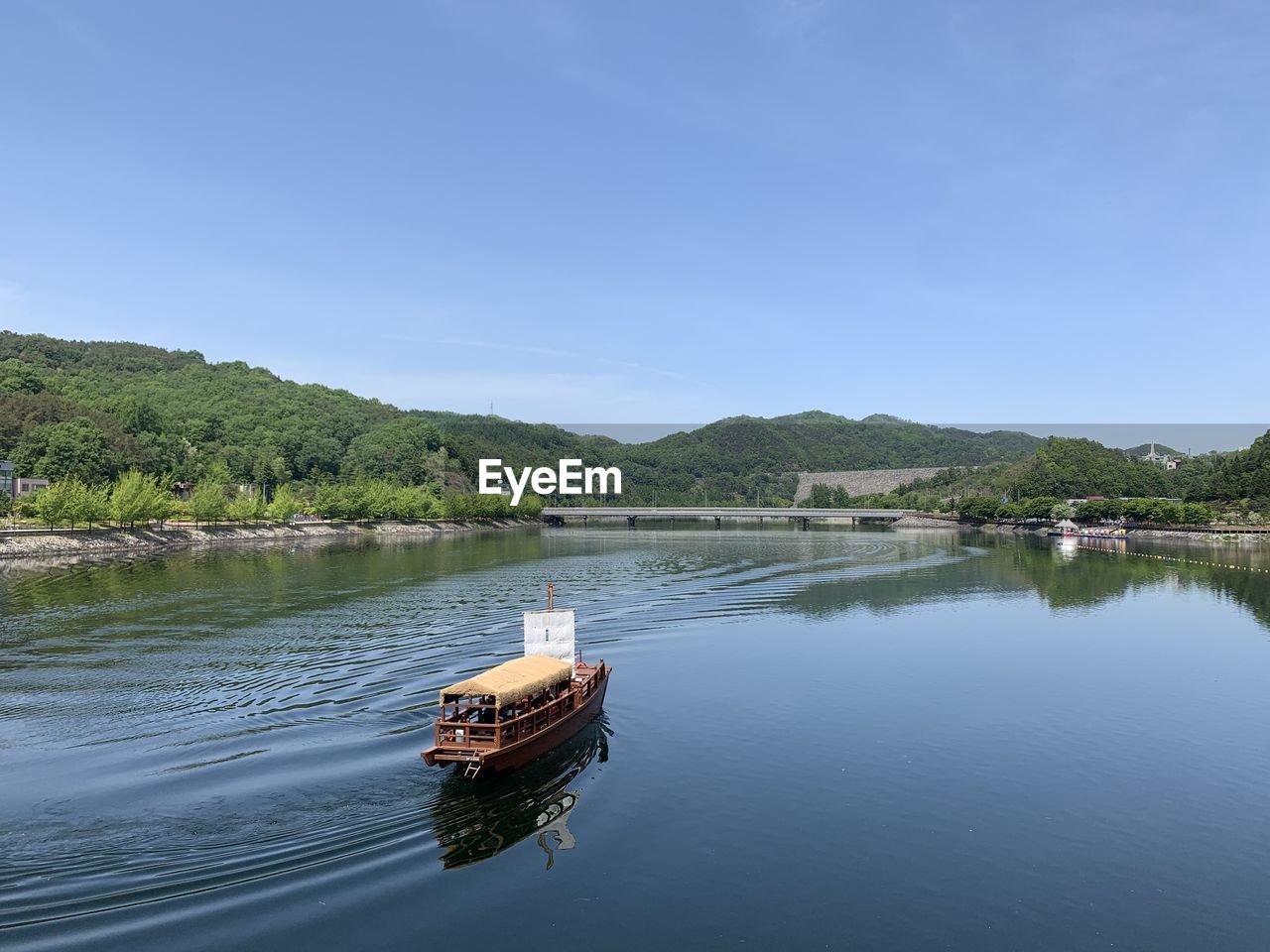 BOAT ON RIVER AGAINST BLUE SKY