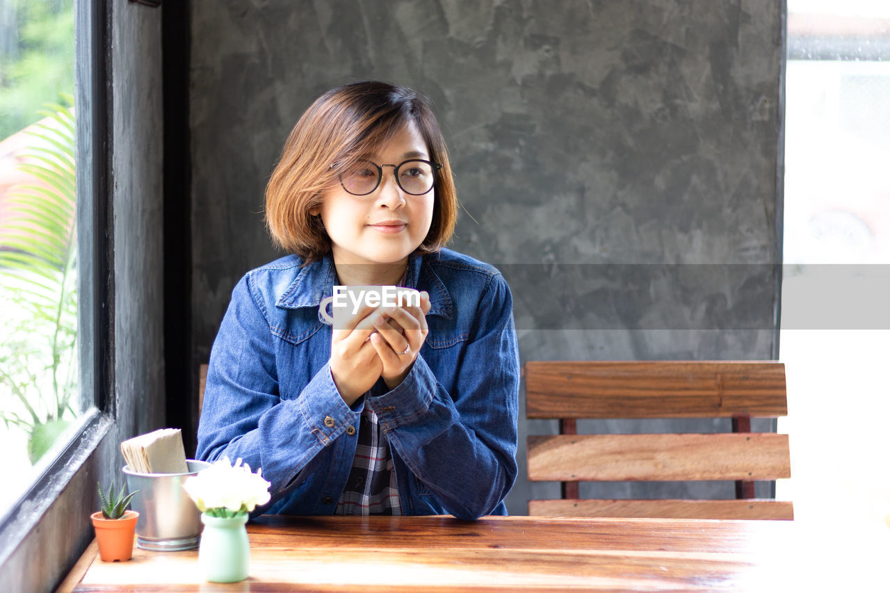 PORTRAIT OF WOMAN SITTING IN CAFE