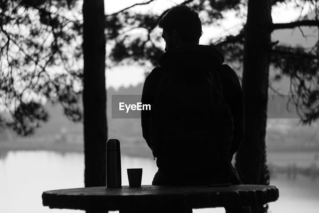 Rear view of silhouette man sitting on table