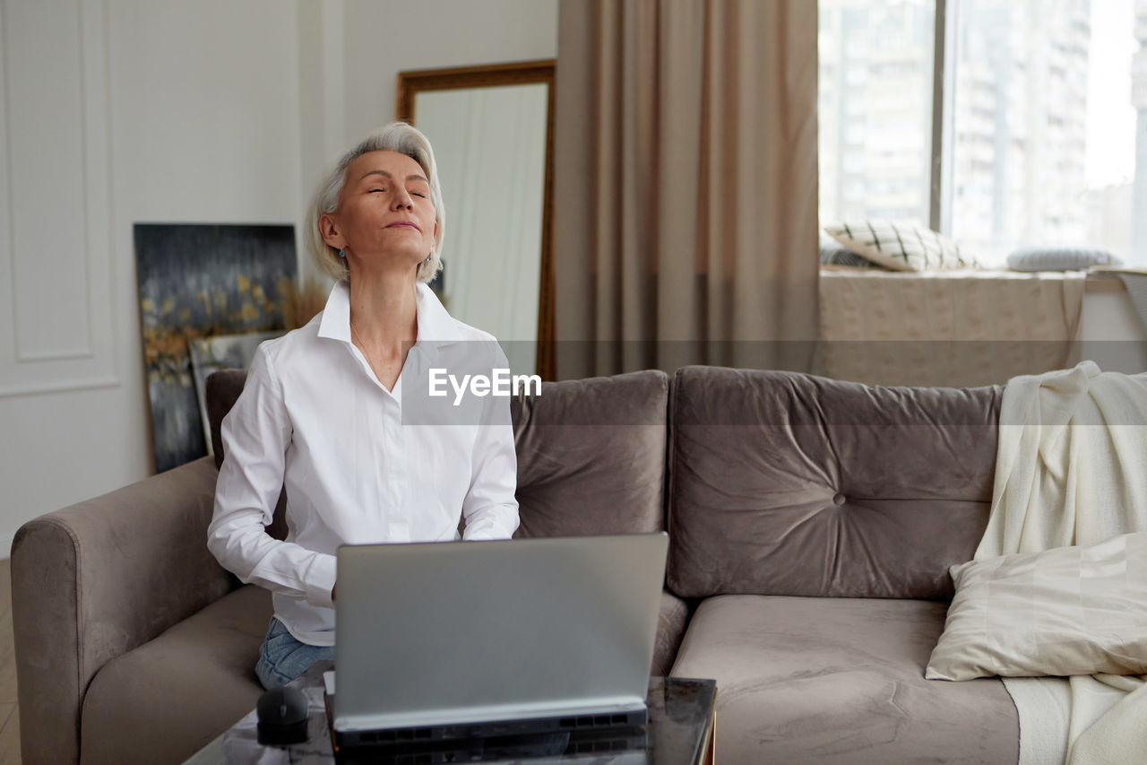 Businesswoman meditating during work from home in living room