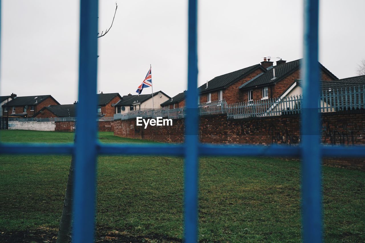 Houses against sky seen through fence