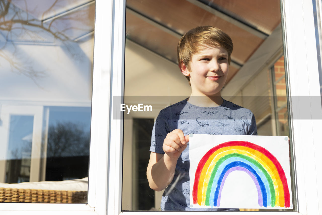 FULL LENGTH PORTRAIT OF BOY HOLDING MULTI COLORED BOAT