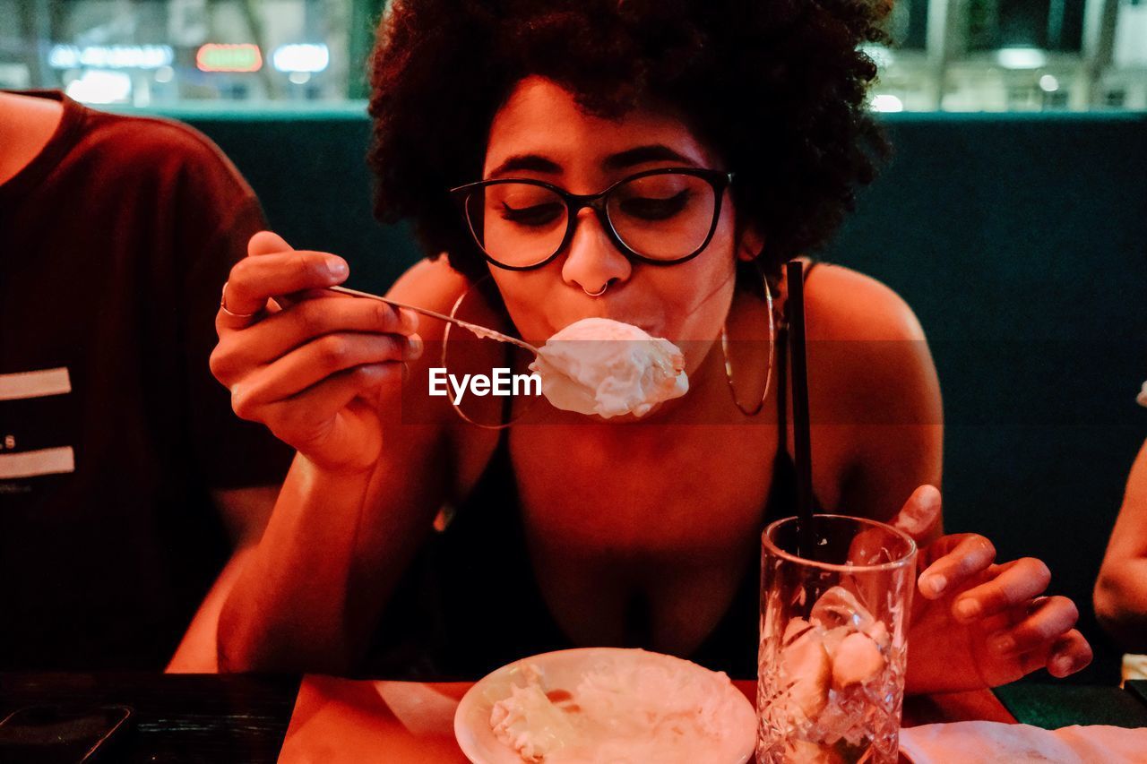 MIDSECTION OF WOMAN DRINKING GLASS ON TABLE