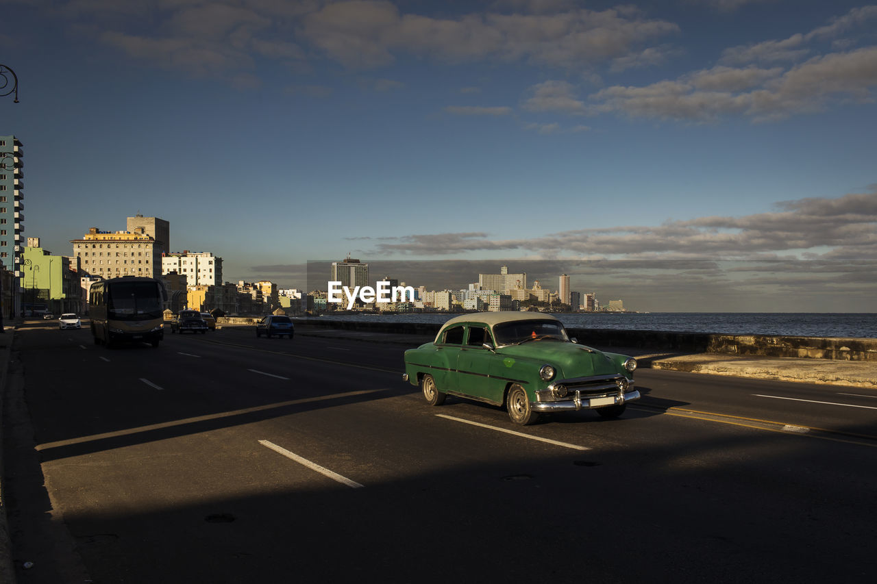 CARS ON ROAD AGAINST CITYSCAPE