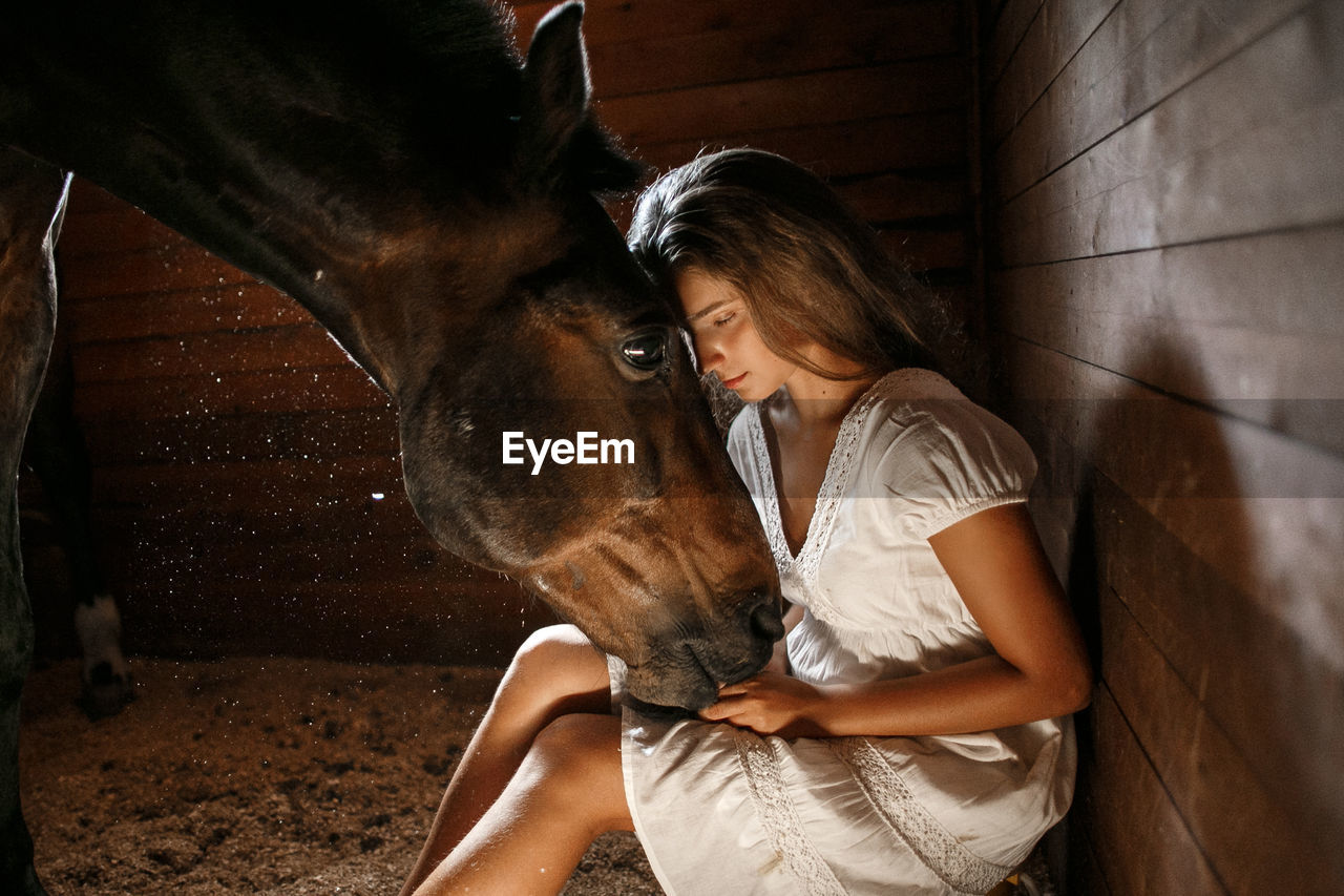 Woman stroking horse in stable