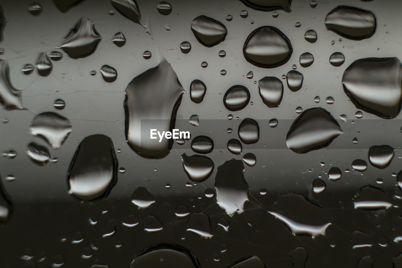 FULL FRAME SHOT OF WET GLASS WITH WATER DROPS