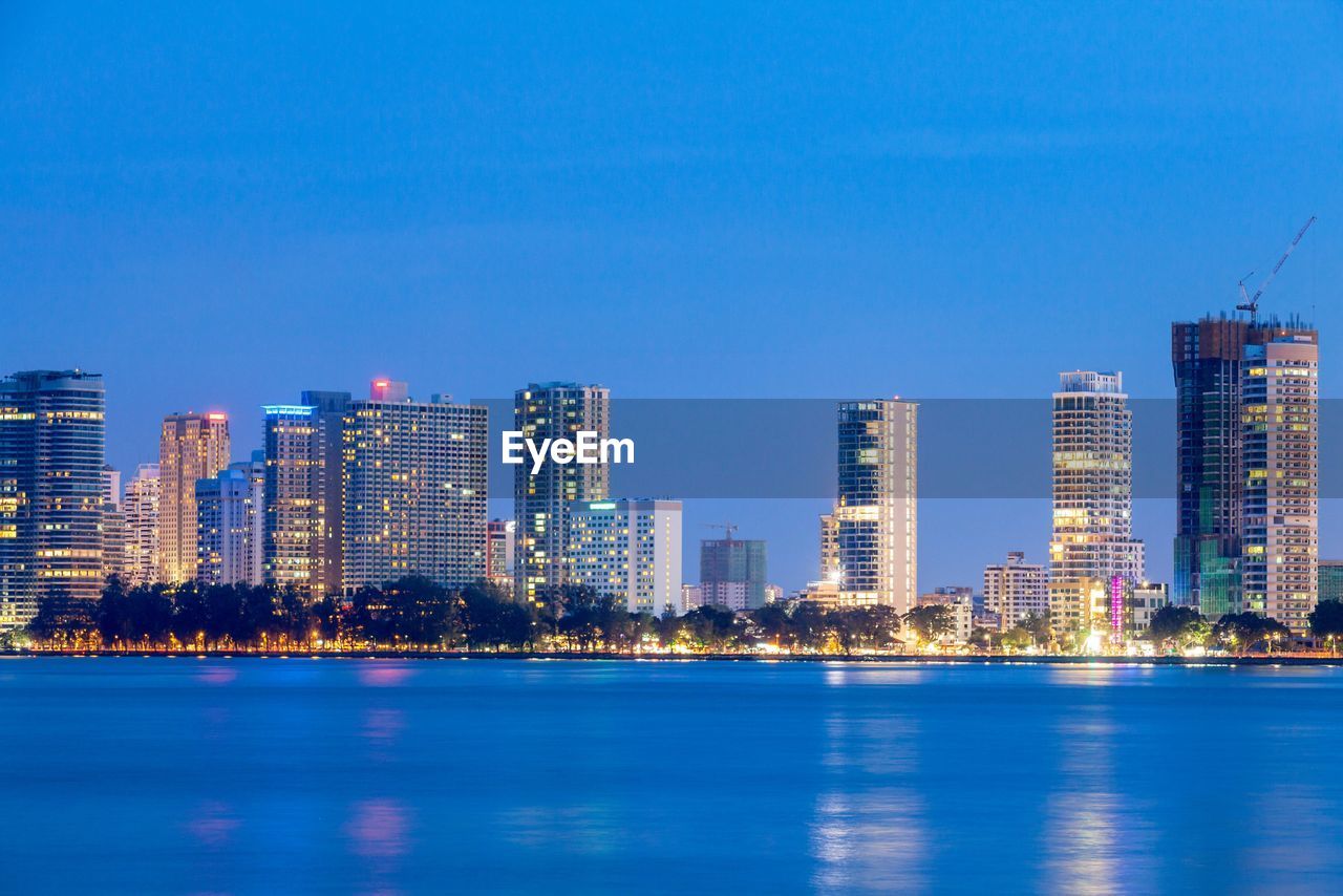 Illuminated cityscape against clear blue sky