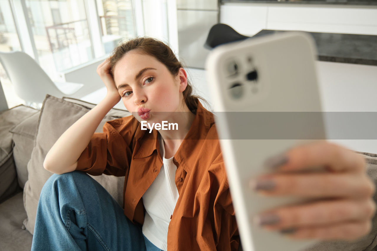 portrait of young woman using mobile phone while sitting on table